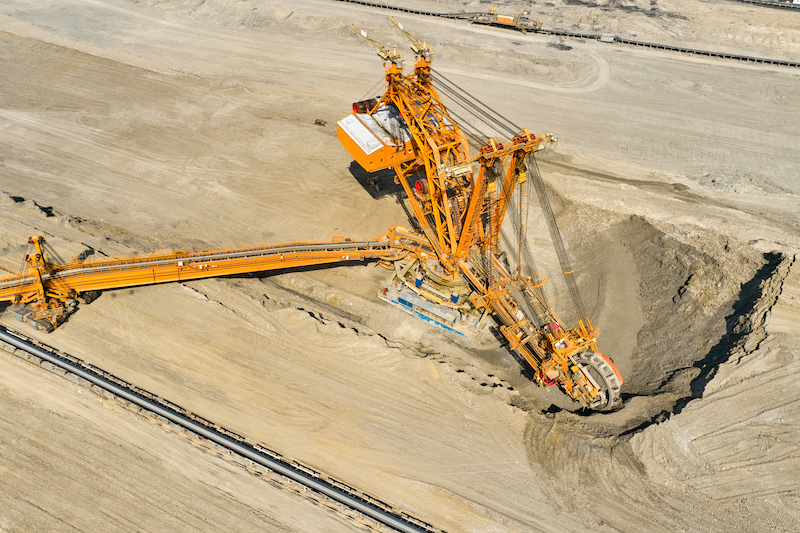 Huge bucket wheel excavator or mobile strip mining machine mining coal in a quarry. Heavy industry concept.